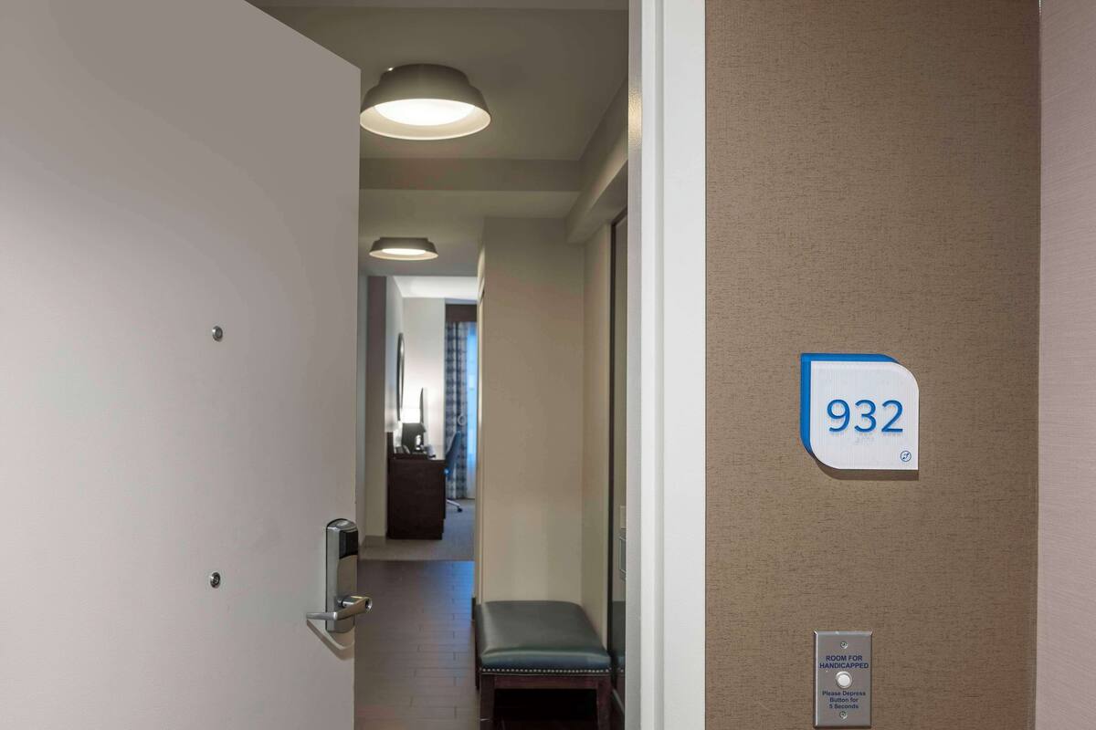 A hallway with a door leading to room 932, a bench, and a sign indicating a room for handicapped individuals.