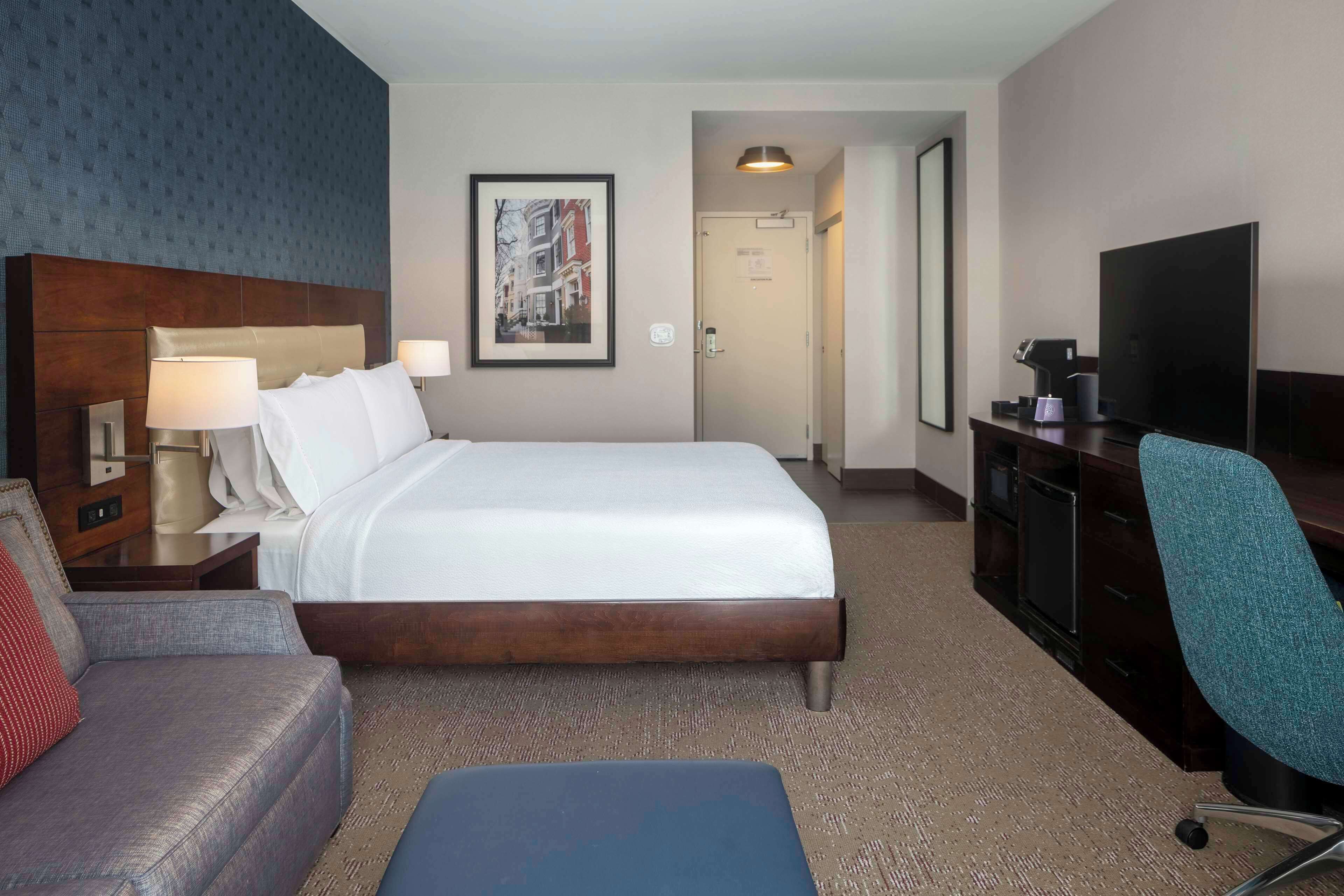 Een hotelkamer met een groot bed, een bureau met een computer, een televisie en een bank.