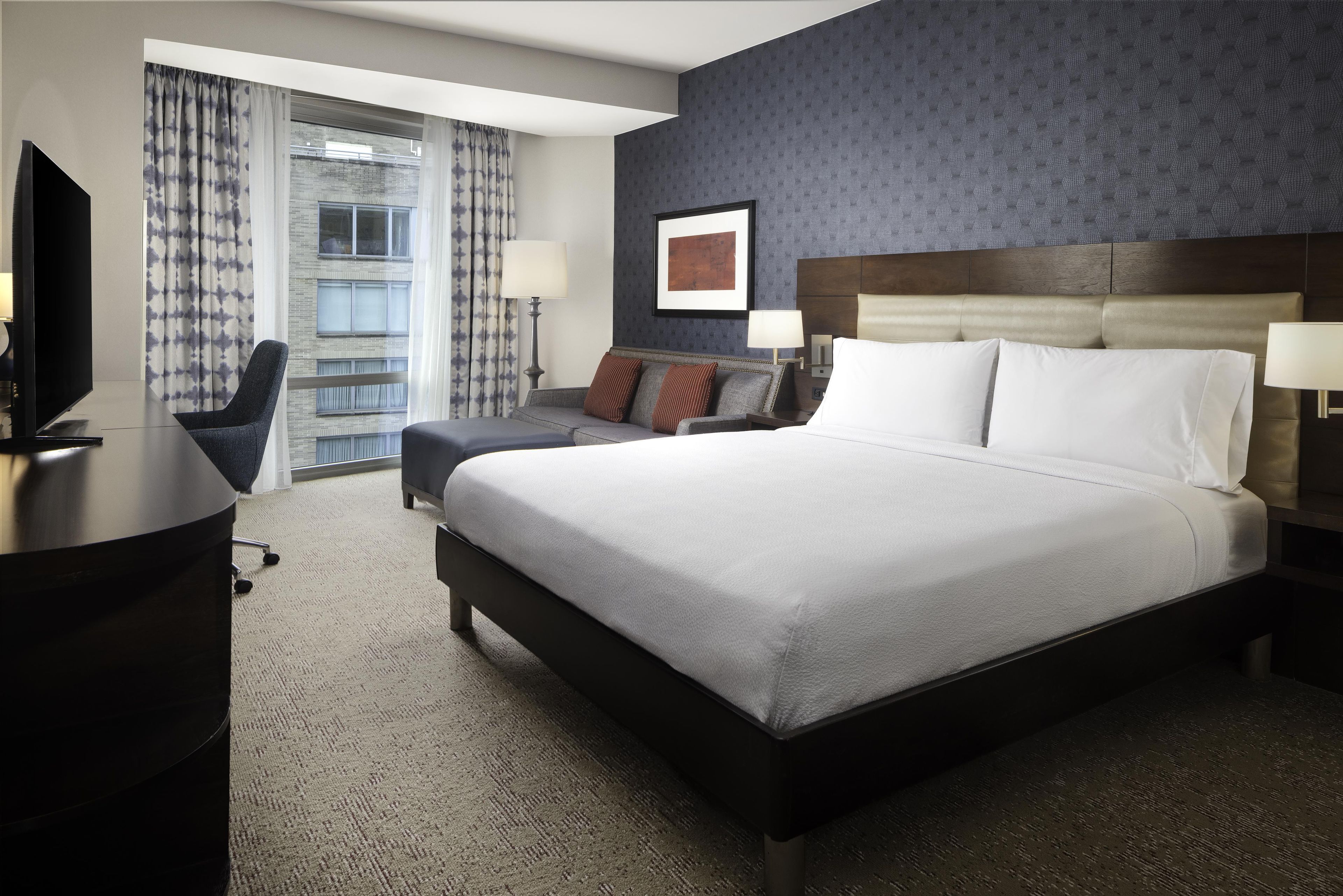 Una habitación de hotel con una cama grande, un escritorio, una silla y un televisor.