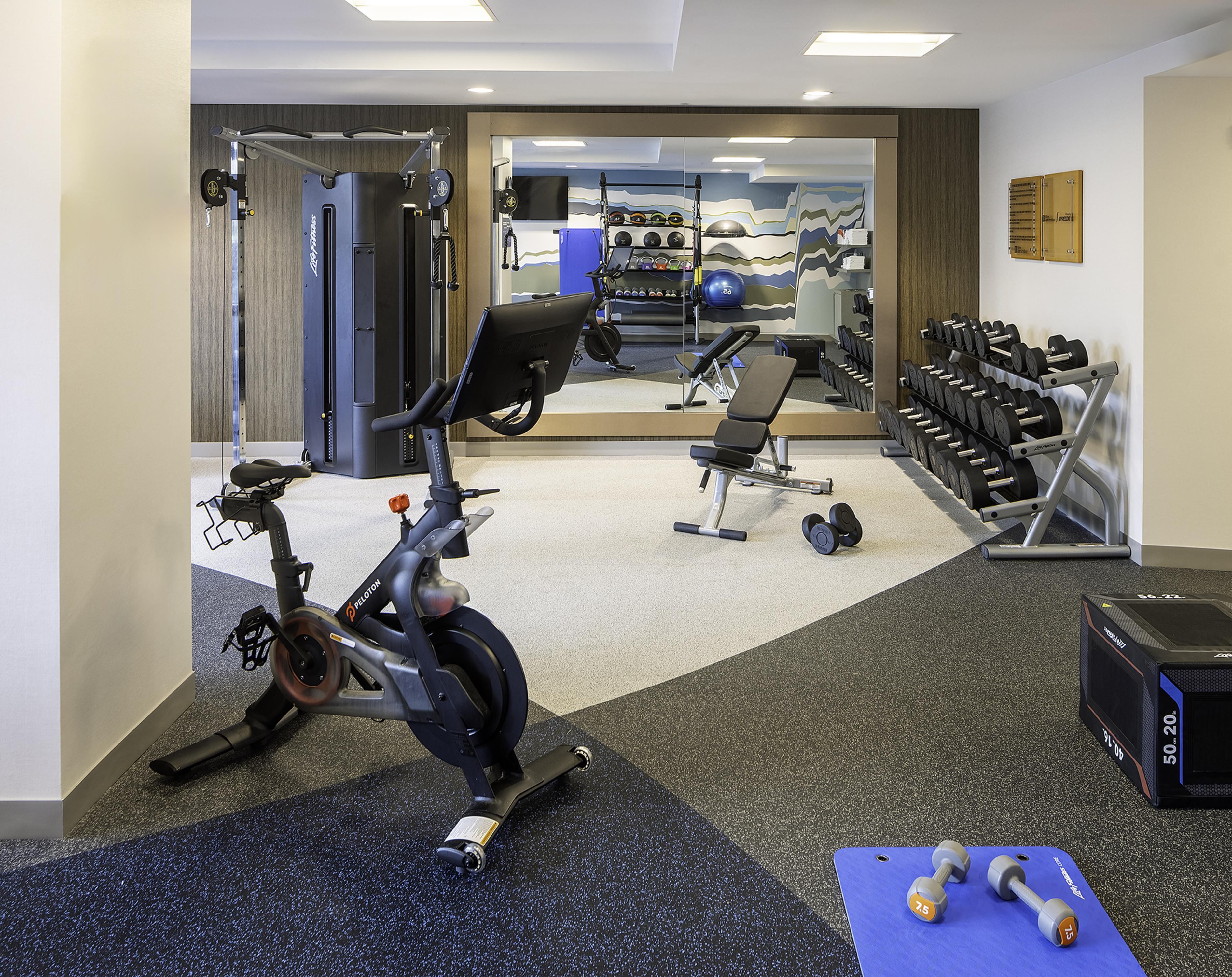 A gym with cardio equipment, weight machines, and dumbbells.