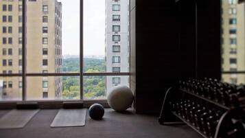 A room with a large window, exercise balls, and a rack of dumbbells.