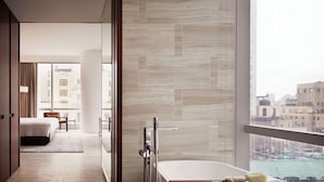 A modern bathroom with a bathtub, a glass shower enclosure, and a view of the city through large windows.