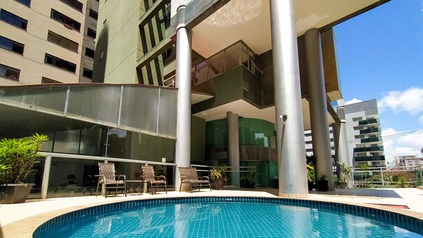 A swimming pool with tiled edges, surrounded by lounge chairs and potted plants. - Savassi Village (Belo Horizonte)