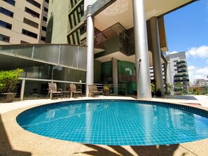 A swimming pool with tiled edges, surrounded by lounge chairs and potted plants. - Savassi Village (Belo Horizonte)