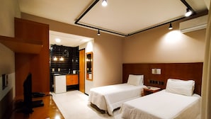 A hotel room with two beds, a desk, a mirror, and a kitchenette. - Savassi Village (Belo Horizonte)