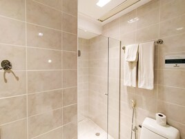 Un baño moderno con cabina de ducha de vidrio, inodoro y perchero.