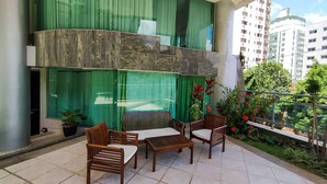 A balcony with a table and chairs, green curtains, and a view of a cityscape. - Savassi Village (Belo Horizonte)