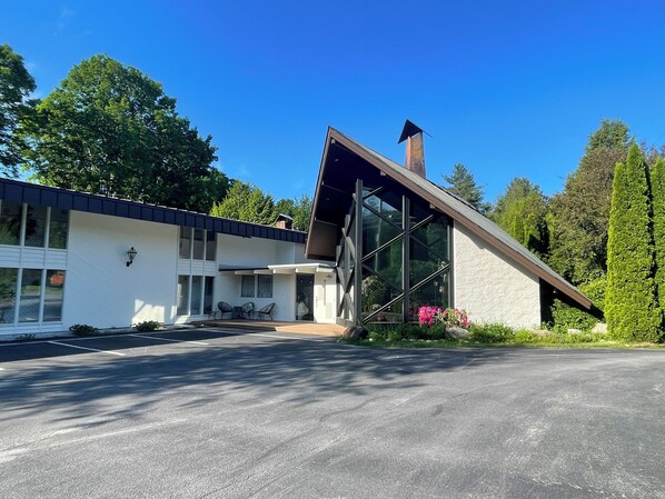 A modern house with a sloped roof, large windows, and a visible chimney. - Toll Road Inn (Manchester Center)