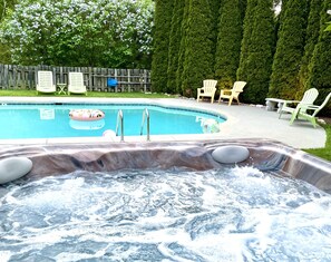 A hot tub with a waterfall feature, a swimming pool, and outdoor seating. - Toll Road Inn (Manchester Center)
