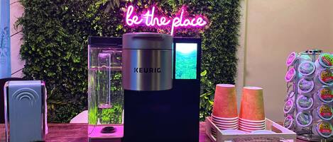 A coffee machine with a screen, a neon sign, and a display of coffee pods.