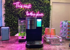A coffee machine with a screen, a neon sign, and a display of coffee pods. - Toll Road Inn (Manchester Center)