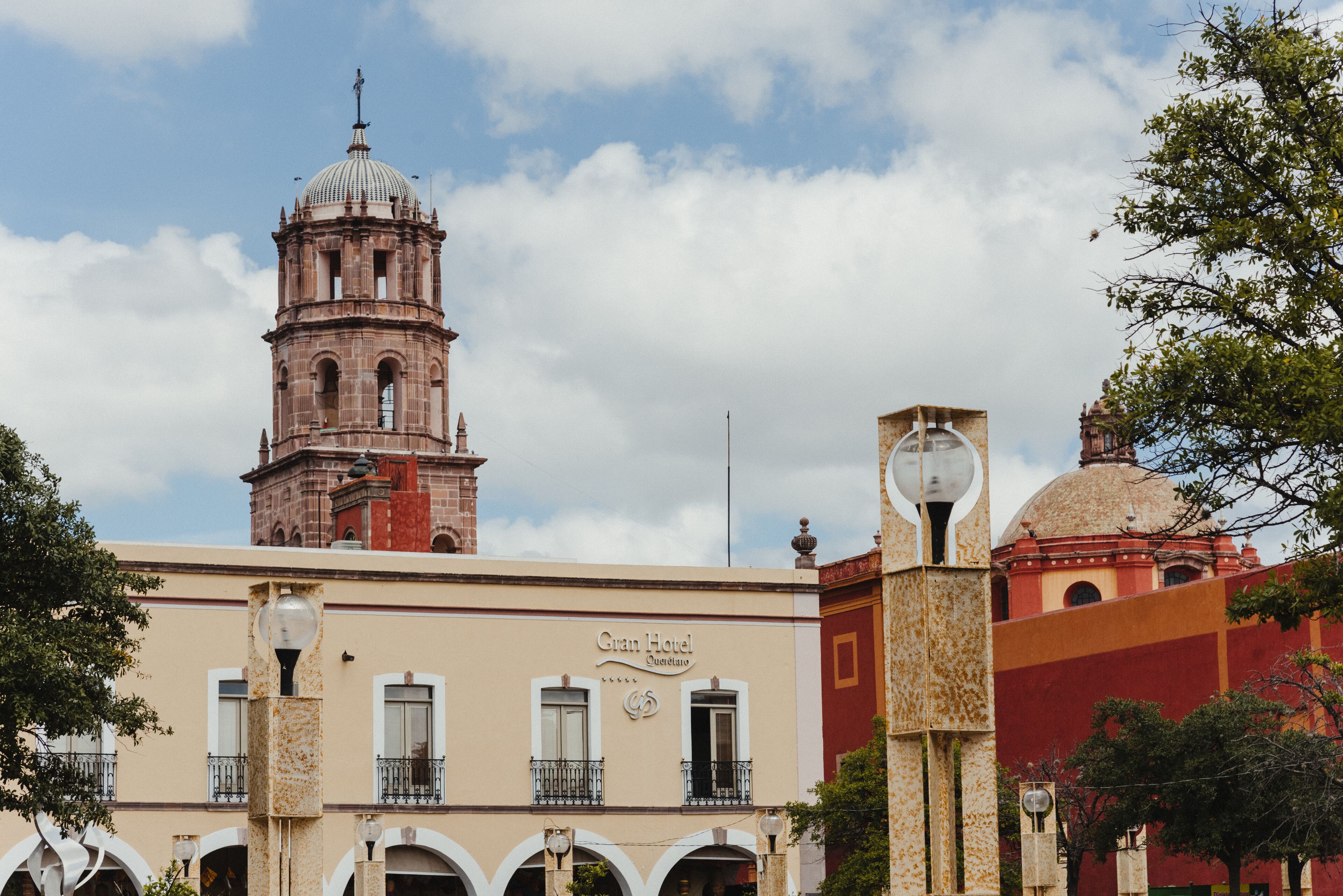A hotel with a prominent clock tower and a dome, featuring balconies and a classic architectural style.