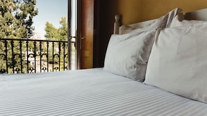 A bed with white bedding and a view of a balcony with a metal railing. - Gran Hotel de Querétaro (Querétaro)