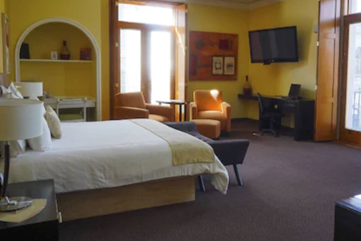 A hotel room with a bed, a desk, a chair, a TV, and a balcony.