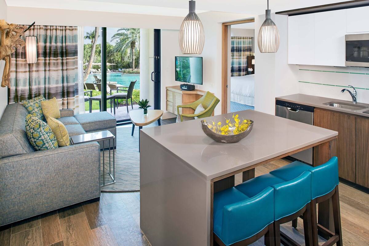 Una cocina moderna con una isla central, taburetes de bar y una zona de comedor con sofá y sillas.