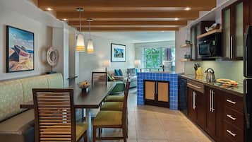 A modern kitchen with wooden cabinets, a blue tiled backsplash, and a dining area with a wooden table and chairs.