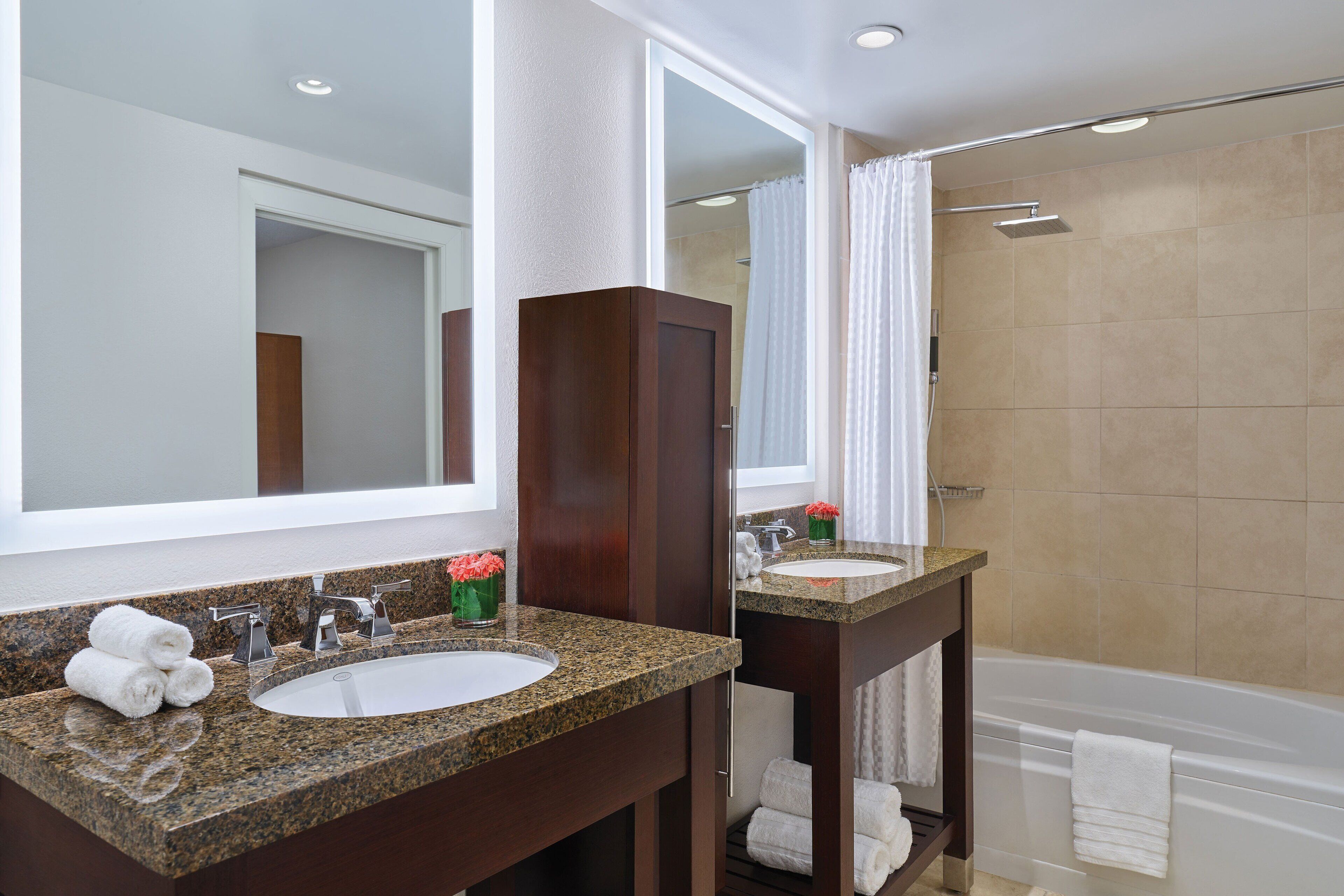 A modern bathroom with two sinks, a large mirror, and a shower.