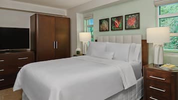 A hotel room with a large bed, a TV, a wardrobe, and artwork on the wall.