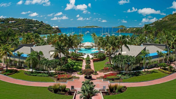 Un resort con piscina central, palmeras y vista al océano.