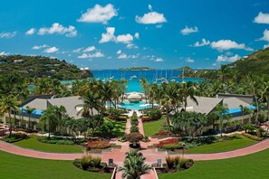 Un resort con piscina central, palmeras y vista al océano.