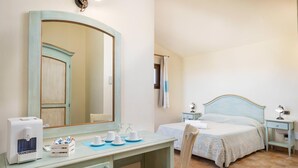 Een slaapkamer met een bed, nachtkastjes, een bureau met een spiegel en een stoel.