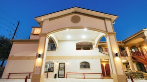 A multi-story hotel with a central entrance, balconies, and a staircase. - Palace Inn Fairbanks (Houston)