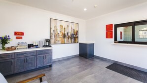 A reception area with a counter, cabinets, a painting, and informational signs. - Palace Inn Fairbanks (Houston)