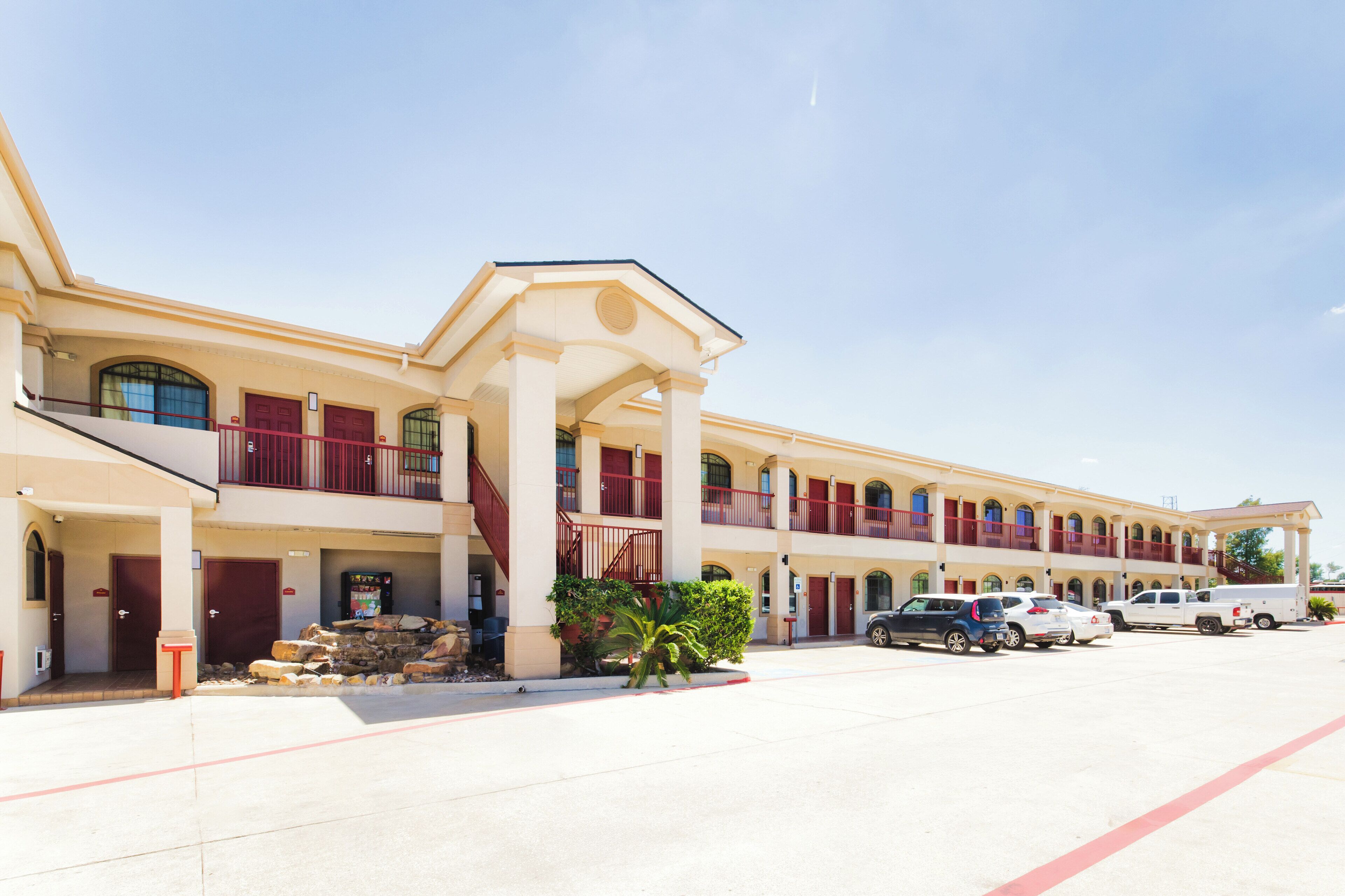 A multi-story hotel with a central atrium, balconies, and a parking lot.