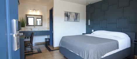 Une chambre moderne avec un grand lit, un bureau avec une chaise, un lavabo et un miroir.