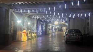 L’entrée d’un hôtel, avec un trottoir mouillé, des décorations de Noël illuminées et une voiture garée.