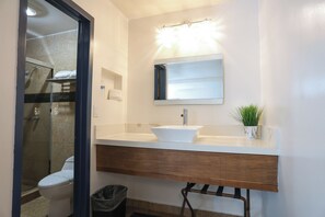 A bathroom with a white sink, a mirror, and a shower.