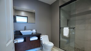 Une salle de bain moderne avec une douche à parois de verre, un meuble-lavabo en bois foncé et des toilettes blanches.