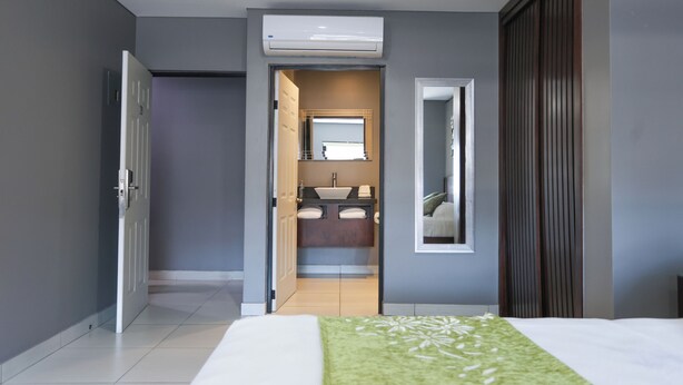 Une chambre d’hôtel comprenant un lit, une salle de bain avec un lavabo et un miroir, et une armoire.