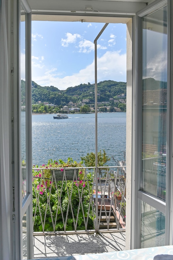 A balcony with a view of a lake, a boat, and a mountainous landscape. - Hotel Marco's (Como)