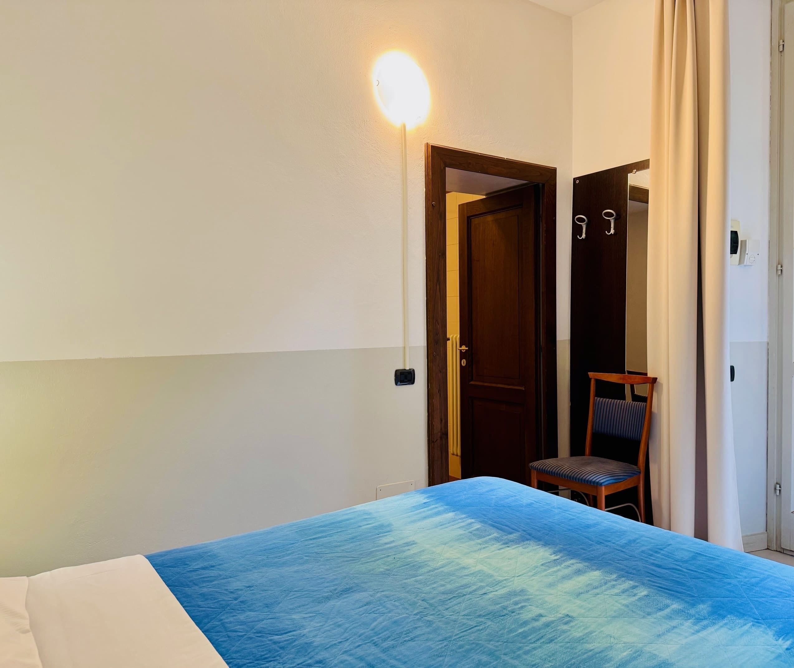 Un dormitorio con cama, una silla, un armario y una puerta.