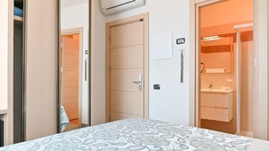 A bedroom with a bed, a wardrobe, and a bathroom with a sink and mirror. - Hotel Marco's (Como)