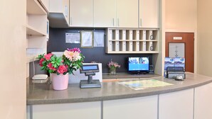 A hotel reception area with a counter, a digital display, a television, and a sign indicating a restaurant. - Hotel Marco's (Como)