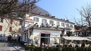 A restaurant with outdoor seating, a mountain backdrop, and a sign indicating it is a restaurant. - Hotel Marco's (Como)