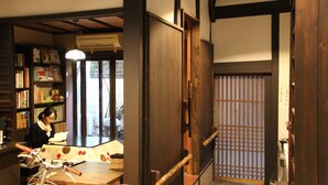 A traditional Japanese room with tatami flooring, a low wooden desk, and a bookshelf filled with books. - HARUYA Higashiyama - Hostel (Kyoto)