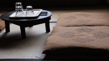 A tatami mat room with a low table, two glasses, and a remote control.