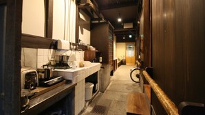 A narrow kitchen with a wooden bench, a sink, and various kitchen appliances. - HARUYA Higashiyama - Hostel (Kyoto)