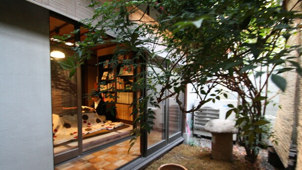 A cozy room with a large window, a wooden floor, and a small indoor garden with a potted plant. - HARUYA Higashiyama - Hostel (Kyoto)