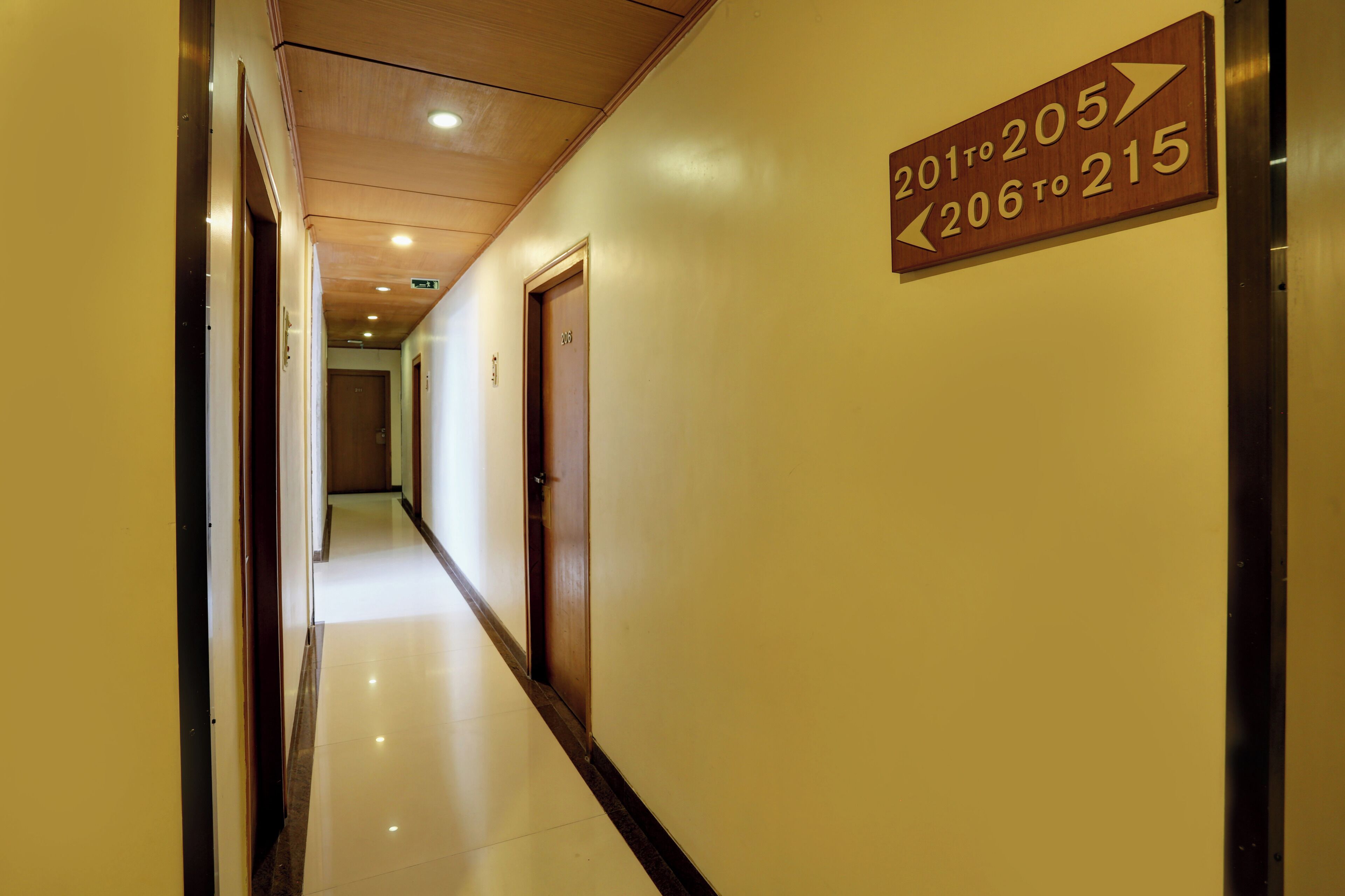 A hotel corridor with directional signs indicating room numbers 201 to 205 and 206 to 215.