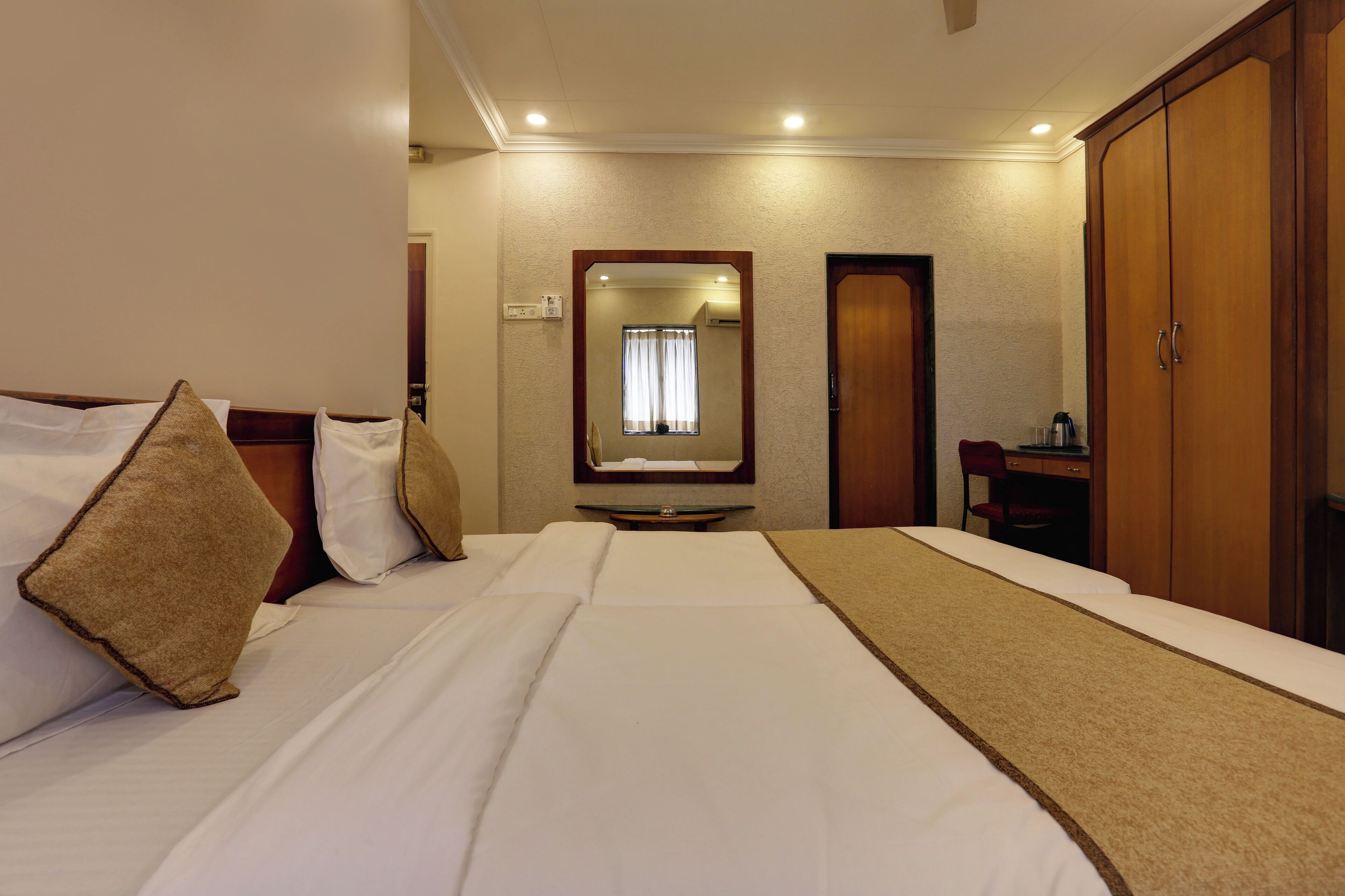 Una habitación de hotel con cama, espejo, armario y escritorio con silla.