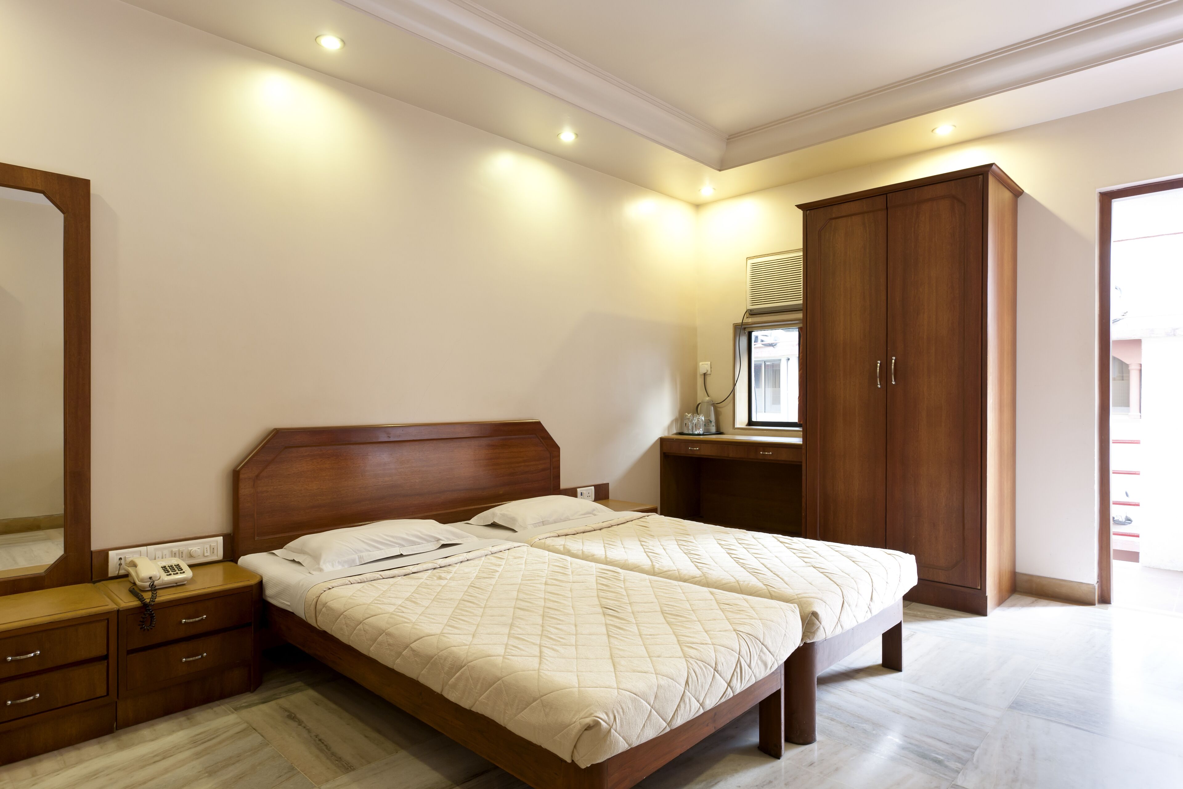 A bedroom with a double bed, wooden nightstands, a wardrobe, and a mirror.