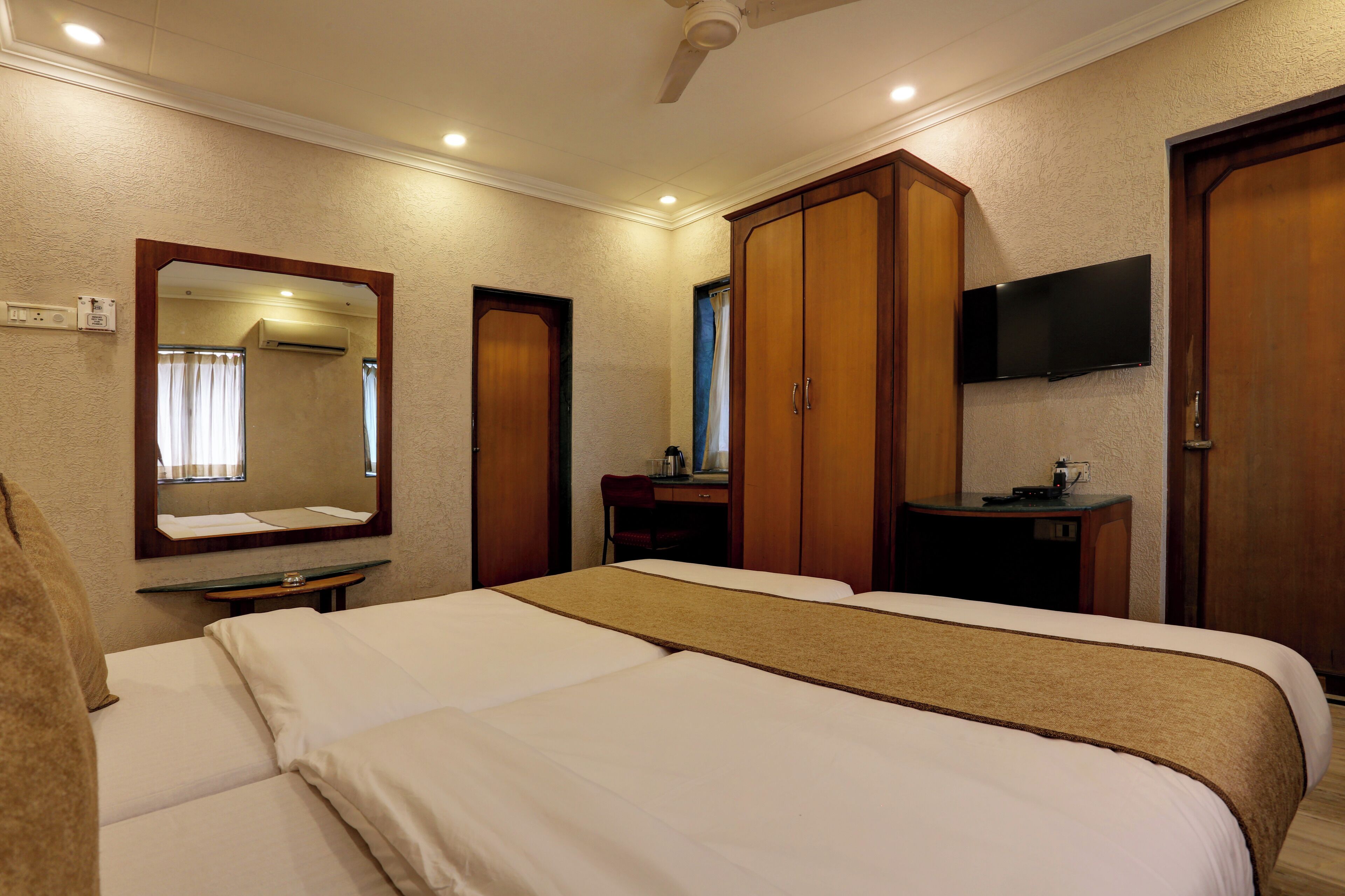 Habitación de hotel con dos camas, televisión, escritorio y armario.