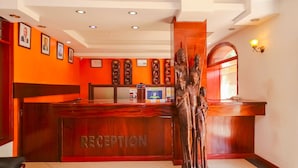 A reception desk with a wooden finish and the word "RECEPTION" on it. There are framed pictures on the wall above the desk. - Nairobi Upperhill Hotel (Nairobi)