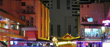 A brightly lit urban area with a prominent yellow building featuring multiple air conditioning units.