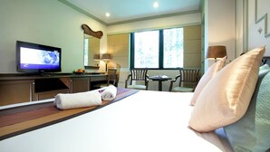 A hotel room with a bed, a television, a desk, a chair, and a window. - Majestic Suites (Bangkok)