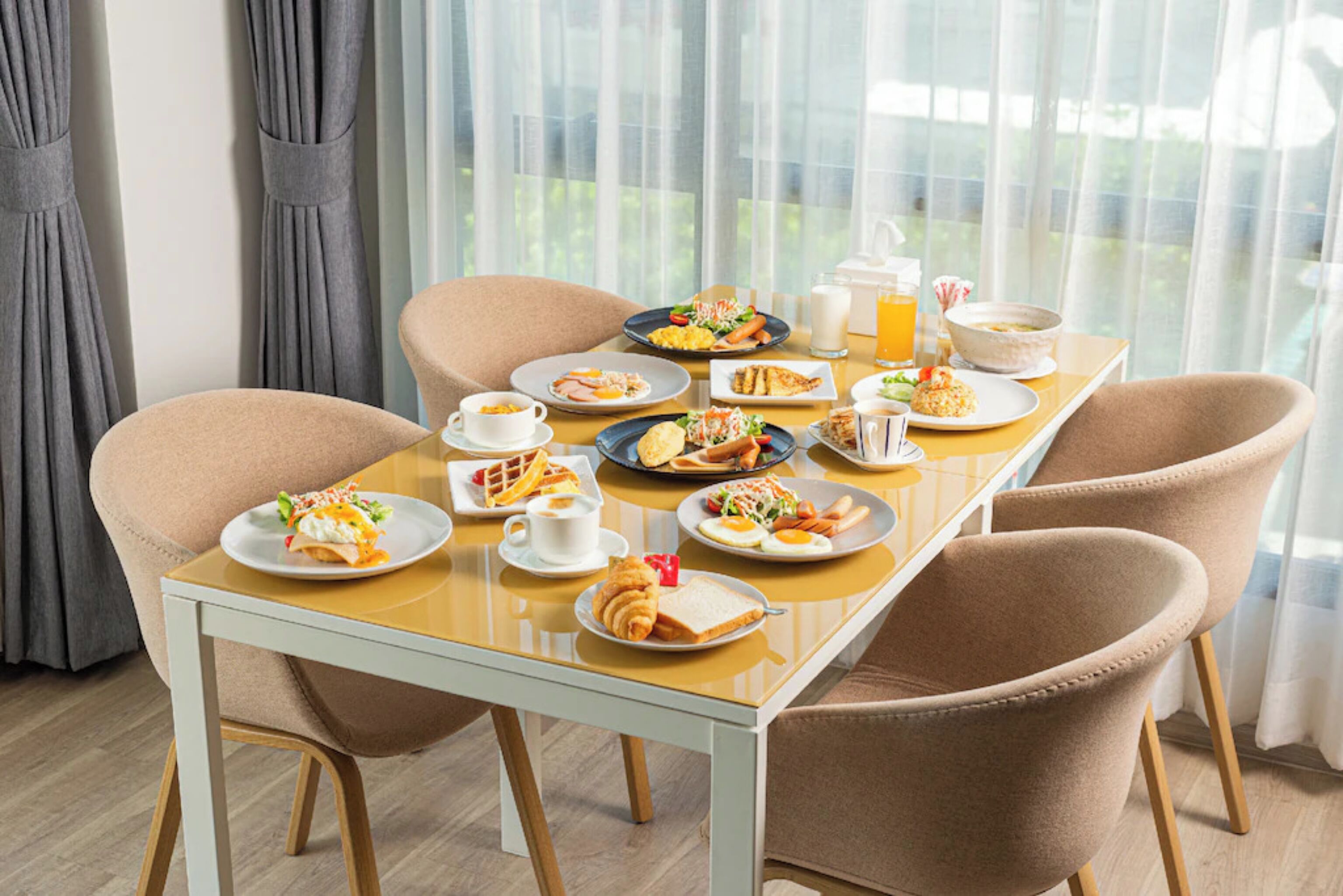 A breakfast table set with plates of food, cups, and a pitcher of orange juice.